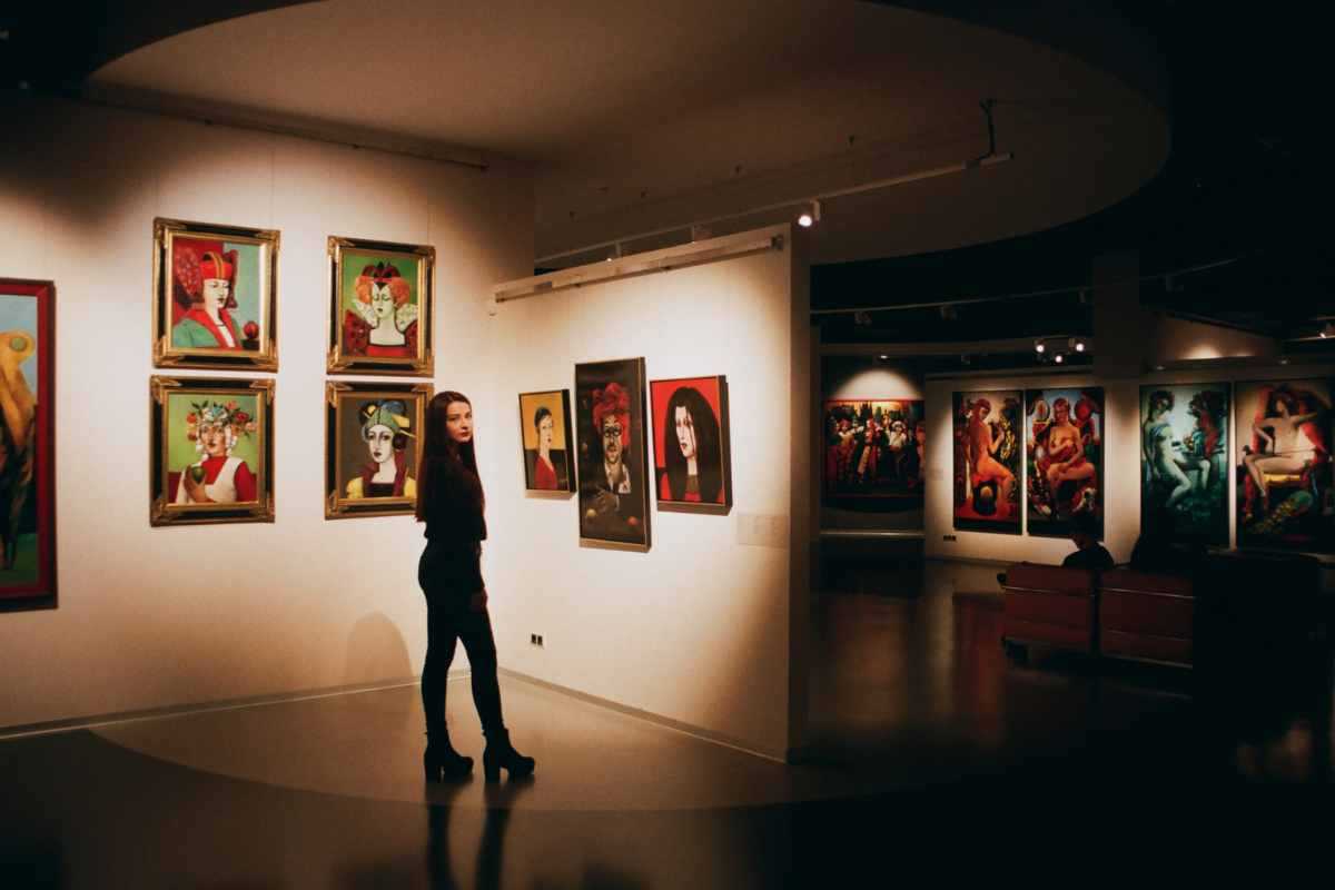 Stanza con quadri e donna che visita la mostra