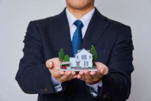 uomo con casa in miniatura in mano
