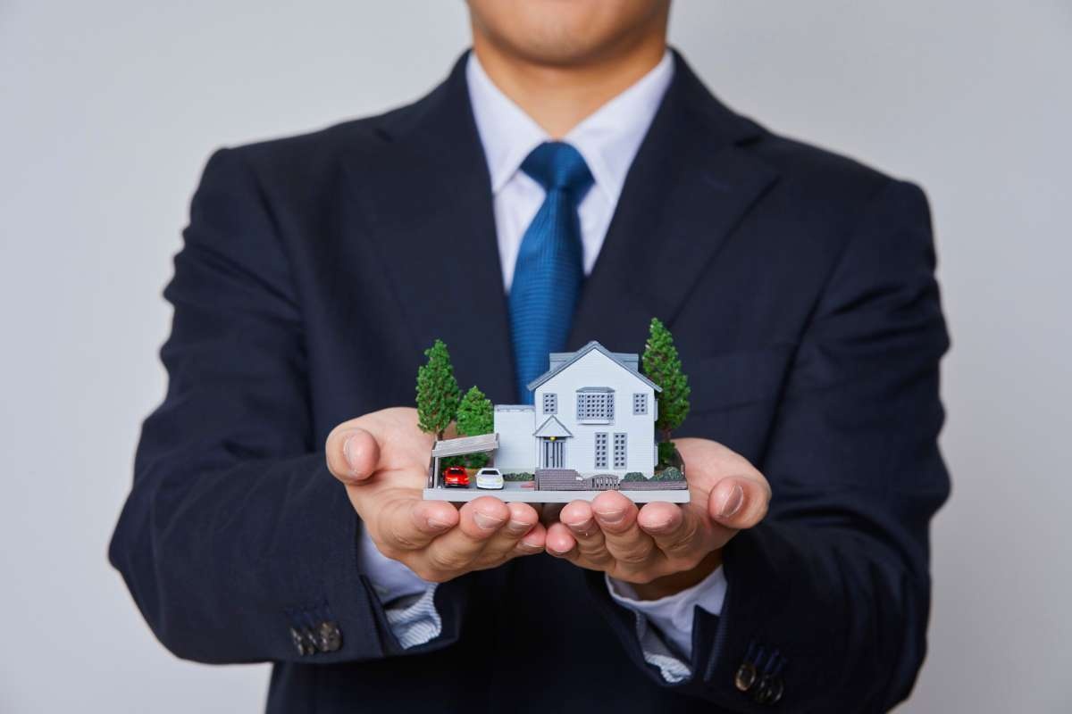 uomo con casa in miniatura in mano