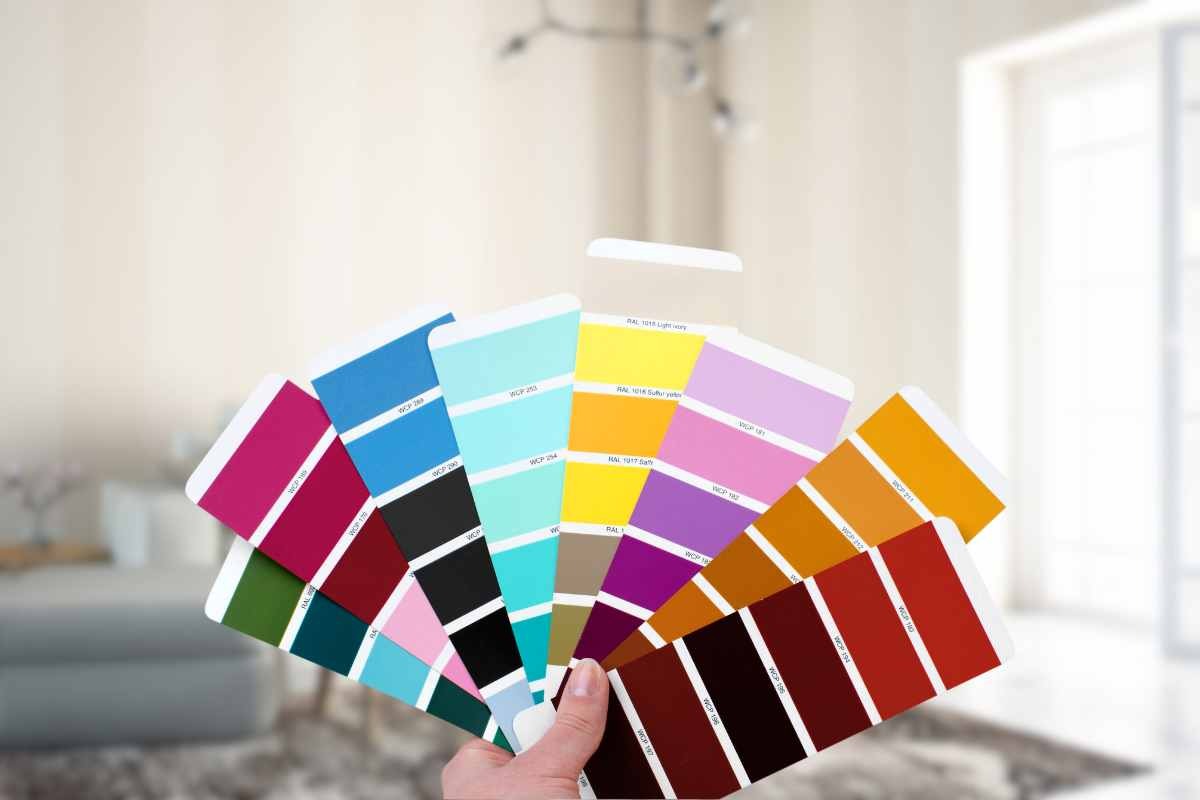 palette di colori in mano e soggiorno di casa come sfondo