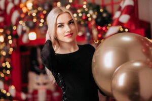 ragazza in una casa addobbata per Natale e due palloncini