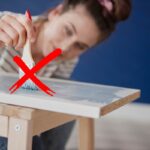 ragazza che vernicia asse di legno
