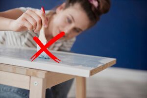 ragazza che vernicia asse di legno